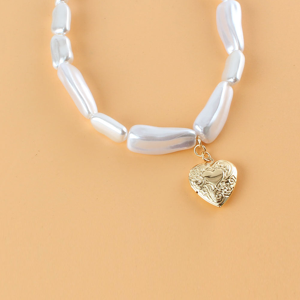 Bracelet with white beads and a gold heart-shaped charm on a beige background